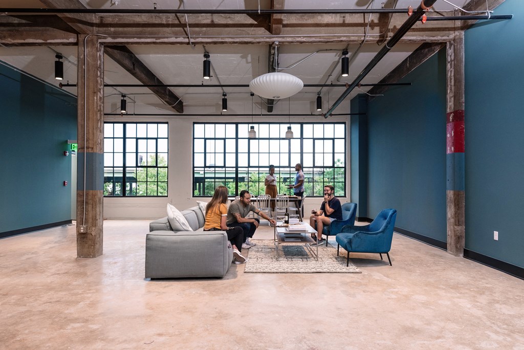 a group of people sitting in a living room with blue walls and large windows